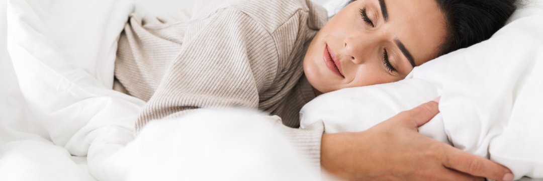 Une femme dort dans de la literie blanche