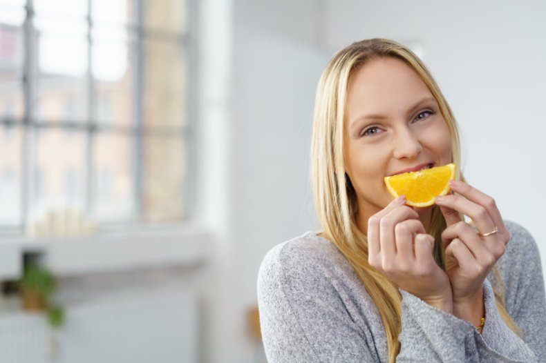 Femme assise dans une pièce lumineuse et est un morceau d'orange