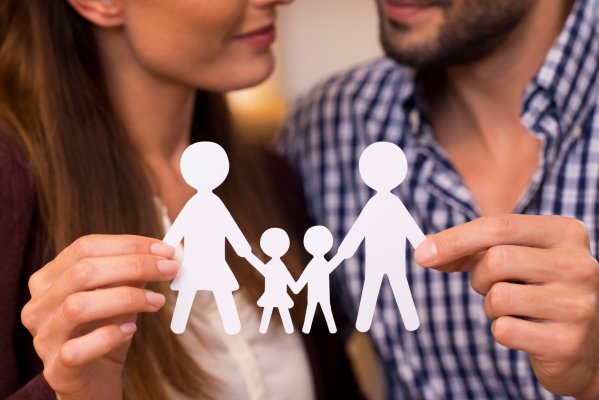 Paar h&auml;lt symbolisch eine Familie aus Papier in den H&auml;nden