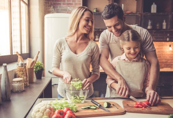 Père, mère et enfant découpant ensemble les légumes