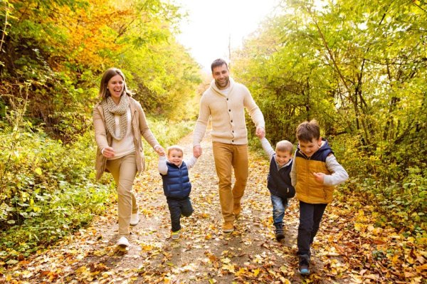 Junge Familie mit 3 Kindern bei einem Spaziergang im Herbstwald