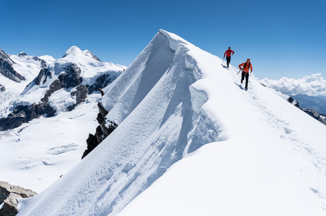 Zwei Männer auf einem Berggipfel mit Schnee bei Sonnenschein