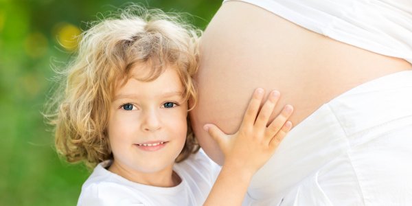 Bauch einer Schwangeren Frau mit einem gr&ouml;sseren Kind, welches den Bauch umarmt