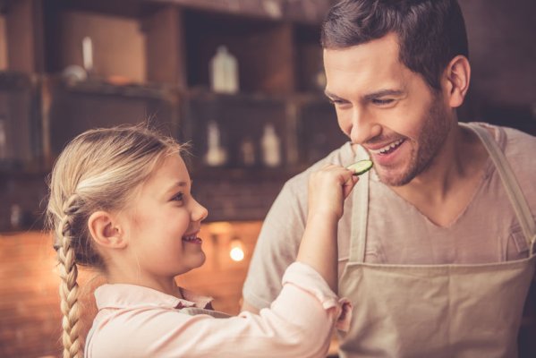 Kleines M&auml;dchen f&uuml;ttert den Vater mit einer Scheibe Gurke