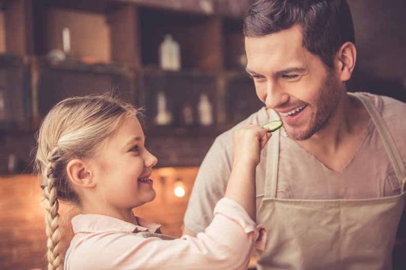 Kleines M&auml;dchen f&uuml;ttert den Vater mit einer Scheibe Gurke