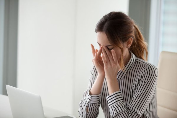 Frau mit Kopfschmerzen vor dem Computer